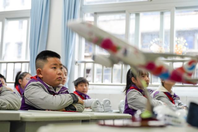 (260306) -- BEIJING, March 6, 2026 (Xinhua) -- Students listen to a flight attendant of Chongqing Airlines explaining civil aviation safety knowledge at the beginning of the new semester at a primary school in Chongqing, southwest China, March 5, 2026. (Xinhua/Liu Chan)