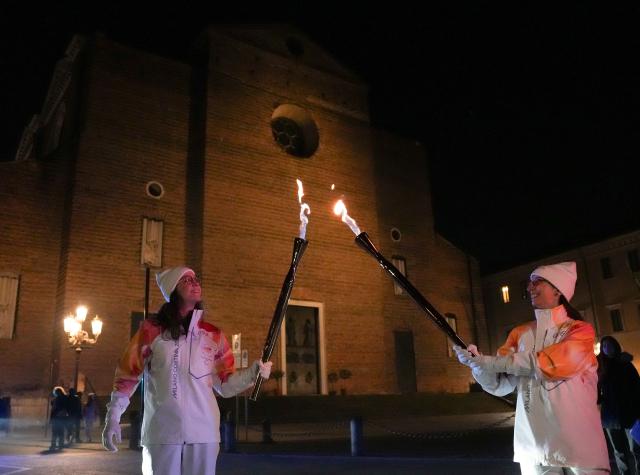 (260306) -- PADUA, March 6, 2026 (Xinhua) -- Torchbearers Elisa Giordano(L) and Annalia Marangio perform torch kiss in front of the Basilica of Santa Giustina during the Milan-Cortina 2026 Paralympic Winter Games Torch Relay in Padua, Italy, March 5, 2025. (Xinhua/Li Jing)