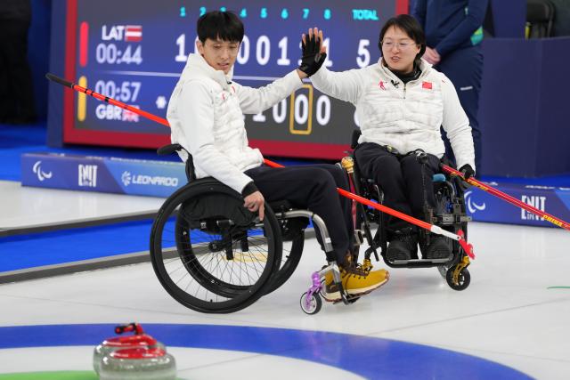 (260306) -- CORTINA D'AMPEZZO, March 6, 2026 (Xinhua) -- Wang Meng (R) and Yang Jinqiao of China celebrate during the wheelchair curling mixed doubles round robin session 3 match between China and Italy at the Milan-Cortina 2026 Paralympic Winter Games in Cortina D'ampezzo, Italy, March 5, 2026. (Xinhua/Lian Yi)