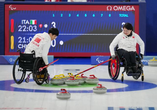 (260306) -- CORTINA D'AMPEZZO, March 6, 2026 (Xinhua) -- Yang Jinqiao (L) and Wang Meng of China compete during the wheelchair curling mixed doubles round robin session 3 match between China and Italy at the Milan-Cortina 2026 Paralympic Winter Games in Cortina D'ampezzo, Italy, March 5, 2026. (Xinhua/Mou Yu)
