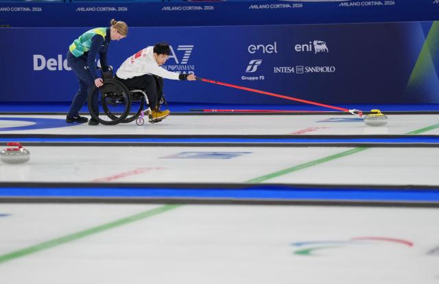 (260306) -- CORTINA D'AMPEZZO, March 6, 2026 (Xinhua) -- Yang Jinqiao (R) of China competes during the wheelchair curling mixed doubles round robin session 3 match between China and Italy at the Milan-Cortina 2026 Paralympic Winter Games in Cortina D'ampezzo, Italy, March 5, 2026. (Xinhua/Mou Yu)
