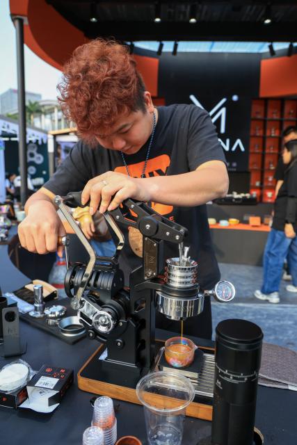 (260306) -- JIANGMEN, March 6, 2026 (Xinhua) -- A staff member uses a hand crank coffee machine during the 4th Jiangmen Coffee Culture Festival in Jiangmen, south China's Guangdong Province, March 5, 2026. The festival kicked off here on Thursday, gathering more than 330 coffee brands from 13 countries and regions to showcase a full range of products including premium coffee, high-quality coffee raw materials, advanced coffee machines and elegant coffee gear. (Xinhua/Mao Siqian)
