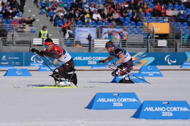 (260307) -- TESERO, March 7, 2026 (Xinhua) -- Wang Tao (L) of China and Scott Meenagh of Britain compete during the men's sprint sitting final of para biathon at the Milan-Cortina 2026 Paralympic Winter Games in Tesero, Italy, March 7, 2026. (Xinhua/Cai Yang)