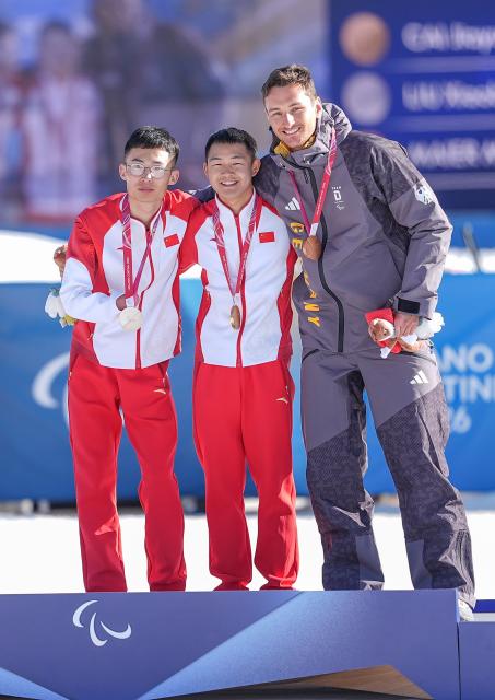 (260308) -- TESERO, March 8, 2026 (Xinhua) -- Gold medalist Cai Jiayun (C) of China celebrates on the podium alongside silver medalist Liu Xiaobin (L) of China and bronze medalist Marco Maier of Germany during the awarding ceremony for the para biathlon men's sprint at the Milan-Cortina 2026 Paralympic Winter Games in Tesero, Italy, March 7, 2026. (Xinhua/Hou Zhaokang)