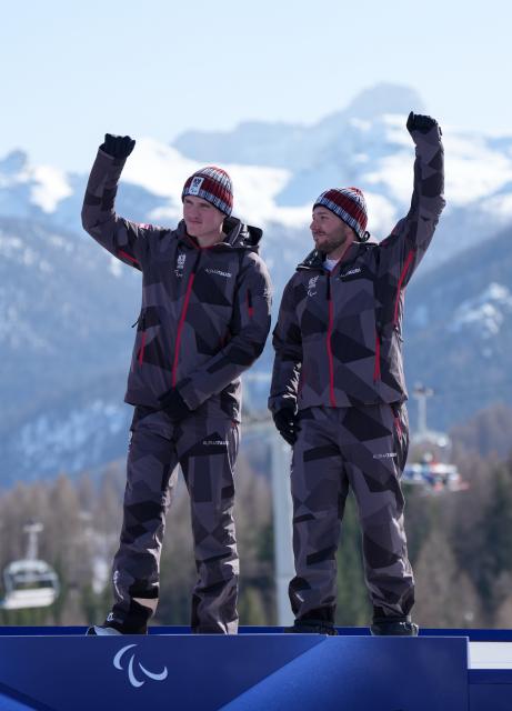 (260308) -- CORTINA D'AMPEZZO, March 8, 2026 (Xinhua) -- Gold medalist Johannes Aigner (L) of Austria celebrates with his guide Nico Haberl during the awarding ceremony for the para alpine skiing men's downhill vision impaired match at the Milan-Cortina 2026 Paralympic Winter Games in Cortina D'ampezzo, Italy, March 7, 2026. (Xinhua/Wang Kaiyan)