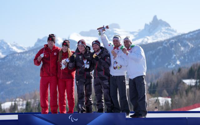 (260308) -- CORTINA D'AMPEZZO, March 8, 2026 (Xinhua) -- Gold medalist Johannes Aigner (3rd L) of Austria, silver medalist Kalle Ericsson (1st L) of Canada, bronze medalist Giacomo Bertagnolli (2nd R) of Italy pose with their guides during the awarding ceremony for the para alpine skiing men's downhill vision impaired match at the Milan-Cortina 2026 Paralympic Winter Games in Cortina D'ampezzo, Italy, March 7, 2026. (Xinhua/Wang Kaiyan)