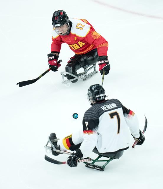 (260308) -- MILAN, March 8, 2026 (Xinhua) -- China's Shen Yifeng (Top) vies with Germany's Leopold Reimann during the Para Ice Hockey preliminary round Group A match between China and Germany at the Milan-Cortina 2026 Paralympic Winter Games in Milan, Italy, March 7, 2026. (Xinhua/Li Jing)