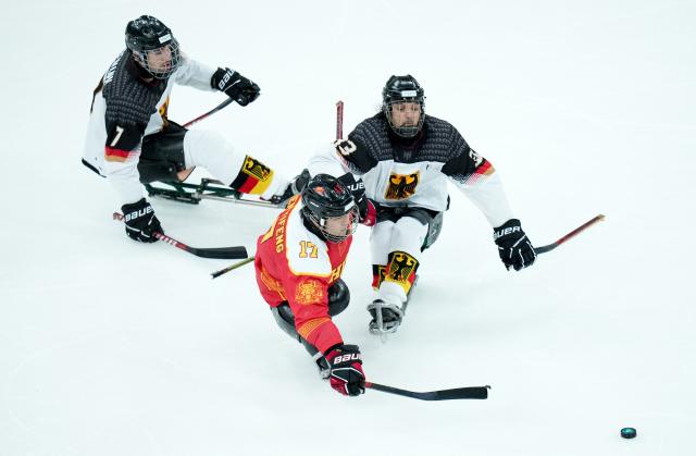 (260308) -- MILAN, March 8, 2026 (Xinhua) -- China's Shen Yifeng (C) vies with Germany's Ingo Kuhli-Lauenstein (R) and Leopold Reimann during the Para Ice Hockey preliminary round Group A match between China and Germany at the Milan-Cortina 2026 Paralympic Winter Games in Milan, Italy, March 7, 2026. (Xinhua/Li Jing)