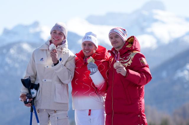 (260308) -- CORTINA D'AMPEZZO, March 8, 2026 (Xinhua) -- Gold medalist Robin Cuche (C) of Switzerland, silver medalist Arthur Bauchet (L) of France, bronze medalist Aleksei Bugaev of Russia react during the awarding ceremony for the para alpine skiing men's downhill standing match at the Milan-Cortina 2026 Paralympic Winter Games in Cortina D'ampezzo, Italy, March 7, 2026. (Xinhua/Wang Kaiyan)