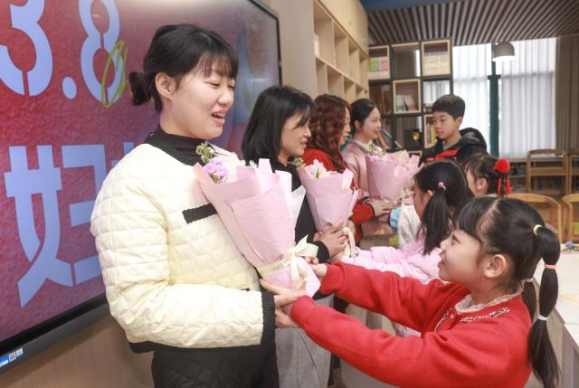 (260308) -- BEIJING, March 8, 2026 (Xinhua) -- Students present flowers to their mothers during an event in celebration of the International Women's Day at a primary school in Hongshan District of Wuhan, central China's Hubei Province, March 8, 2026. Various events were held across China on Sunday to mark the International Women's Day. (Photo by Zhao Jun/Xinhua)