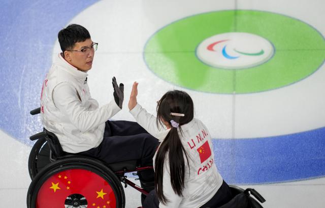 (260310) -- CORTINA D'AMPEZZO, March 10, 2026 (Xinhua) -- Chen Jianxin (L) of China celebrates with teammate Li Nana during the wheelchair curling mixed team round robin session 6 match between China and Norway at the Milan-Cortina 2026 Paralympic Winter Games in Cortina D'ampezzo, Italy, March 9, 2026. (Xinhua/Wang Kaiyan)