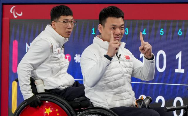 (260310) -- CORTINA D'AMPEZZO, March 10, 2026 (Xinhua) -- Zhang Mingliang (R) of China celebrates after winning the wheelchair curling mixed team round robin session 6 match between China and Norway at the Milan-Cortina 2026 Paralympic Winter Games in Cortina D'ampezzo, Italy, March 9, 2026. (Xinhua/Wang Kaiyan)