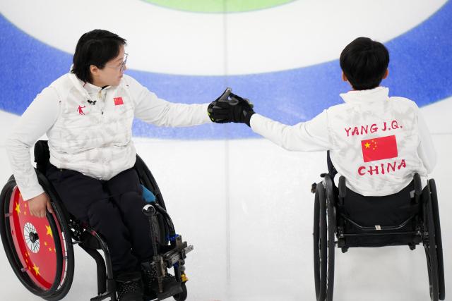 (260310) -- CORTINA D'AMPEZZO, March 10, 2026 (Xinhua) -- Yang Jinqiao/Wang Meng (L) of China clap hands during the wheelchair curling mixed doubles round robin session 7 between China and the United States at the Milan-Cortina 2026 Paralympic Winter Games in Cortina D'ampezzo, Italy, March 9, 2026. (Xinhua/Lian Yi)