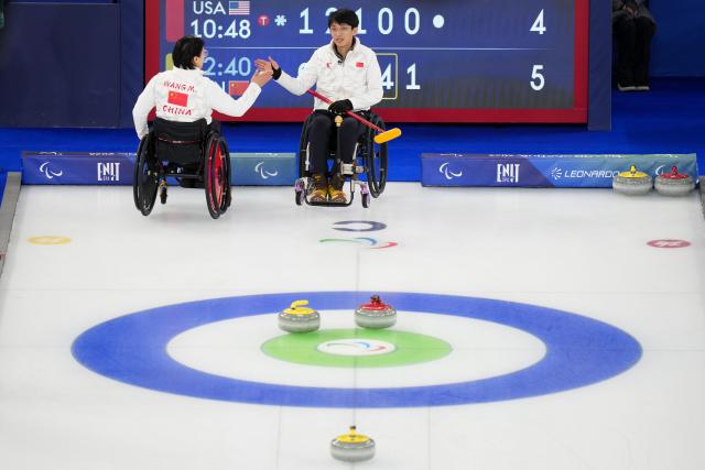 (260310) -- CORTINA D'AMPEZZO, March 10, 2026 (Xinhua) -- Yang Jinqiao (R)/Wang Meng of China clap hands during the wheelchair curling mixed doubles round robin session 7 between China and the United States at the Milan-Cortina 2026 Paralympic Winter Games in Cortina D'ampezzo, Italy, March 9, 2026. (Xinhua/Lian Yi)