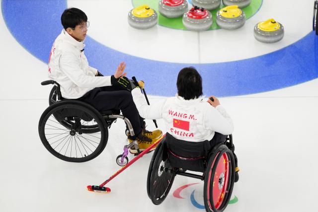 (260310) -- CORTINA D'AMPEZZO, March 10, 2026 (Xinhua) -- Yang Jinqiao (L)/Wang Meng of China clap hands during the wheelchair curling mixed doubles round robin session 7 between China and the United States at the Milan-Cortina 2026 Paralympic Winter Games in Cortina D'ampezzo, Italy, March 9, 2026. (Xinhua/Lian Yi)