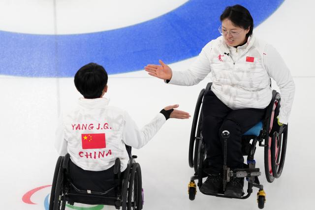 (260310) -- CORTINA D'AMPEZZO, March 10, 2026 (Xinhua) -- Yang Jinqiao/Wang Meng (R) of China clap hands during the wheelchair curling mixed doubles round robin session 7 between China and the United States at the Milan-Cortina 2026 Paralympic Winter Games in Cortina D'ampezzo, Italy, March 9, 2026. (Xinhua/Lian Yi)