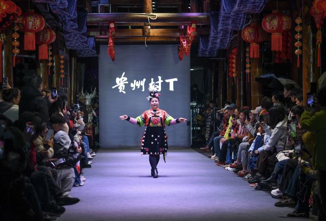 (260310) -- BEIJING, March 10, 2026 (Xinhua) -- An embroiderer presents her work during a "Village T" fashion show in Kaili, Qiandongnan Miao and Dong Autonomous Prefecture, southwest China's Guizhou Province, on March 8, 2026. Embroiderers from Qiandongnan Miao and Dong Autonomous Prefecture participated in the "Village T" fashion show to showcase colorful ethnic costumes. (Xinhua/Yang Wenbin)