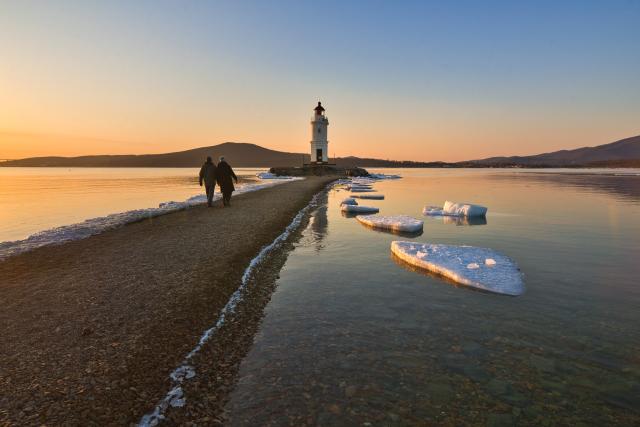 (260310) -- VLADIVOSTOK, March 10, 2026 (Xinhua) -- People walk towards the Tokarevsky Lighthouse at sunrise in Vladivostok, Russia, on March 9, 2026. (Photo by Andrey Matveenko/Xinhua)