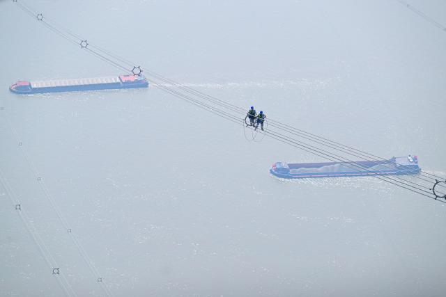 (260310) -- ZONGYANG, March 10, 2026 (Xinhua) -- Maintenance workers check the ±800 kV ultra-high voltage (UHV) Jintang Line over the Yangtze River in Zongyang County of Tongling City, east China's Anhui Province, on March 10, 2026. (Xinhua/Zhou Mu)