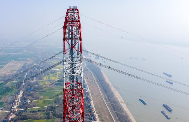 (260310) -- ZONGYANG, March 10, 2026 (Xinhua) -- An aerial drone photo taken on March 10, 2026 shows maintenance workers checking the ±800 kV ultra-high voltage (UHV) Jintang Line by the Yangtze River in Zongyang County of Tongling City, east China's Anhui Province. (Photo by Zhao Xianfu/Xinhua)