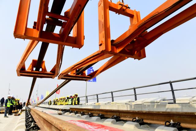 (260310) -- BINZHOU, March 10, 2026 (Xinhua) -- Staff members lay tracks at Binzhou railway station of the Jinan-Binzhou high-speed railway in Binzhou City, east China's Shandong Province, on March 10, 2026. The high-speed railway, which links the province's cities of Jinan and Binzhou and with a designed speed of 350 km/h, has officially entered the full-line track-laying operation phase on Tuesday. (Xinhua/Guo Xulei)