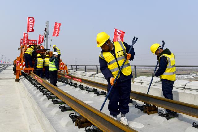 (260310) -- BINZHOU, March 10, 2026 (Xinhua) -- Staff members lay tracks at Binzhou railway station of the Jinan-Binzhou high-speed railway in Binzhou City, east China's Shandong Province, on March 10, 2026. The high-speed railway, which links the province's cities of Jinan and Binzhou and with a designed speed of 350 km/h, has officially entered the full-line track-laying operation phase on Tuesday. (Xinhua/Guo Xulei)