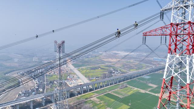 (260311) -- BEIJING, March 11, 2026 (Xinhua) -- An aerial drone photo taken on March 10, 2026 shows maintenance workers checking the ±800 kV ultra-high voltage (UHV) Jintang Line by the Yangtze River in Zongyang County of Tongling City, east China's Anhui Province. (Xinhua/Zhou Mu)