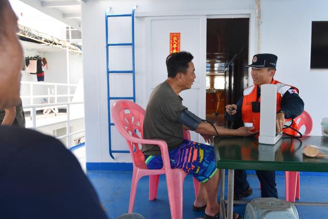 (260311) -- SOUTH CHINA SEA, March 11, 2026 (Xinhua) -- A law enforcer of the China Coast Guard (CCG) vessel Sandu provides medical service to a fisherman in the South China Sea, March 4, 2026. The CCG vessel Sandu conducted patrols in the South China Sea to safeguard China's territorial sovereignty and maritime rights and interests. (Xinhua/Mao Jun)