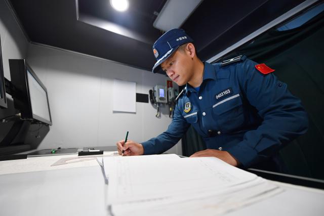 (260311) -- SOUTH CHINA SEA, March 11, 2026 (Xinhua) -- A law enforcer works on maps aboard the China Coast Guard (CCG) vessel Sandu in the South China Sea, March 6, 2026. The CCG vessel Sandu conducted patrols in the South China Sea to safeguard China's territorial sovereignty and maritime rights and interests. (Xinhua/Mao Jun)
