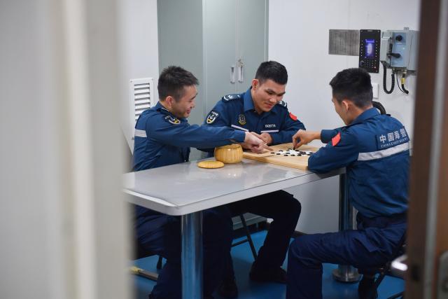 (260311) -- SOUTH CHINA SEA, March 11, 2026 (Xinhua) -- Law enforcers play a board game during their break time aboard the China Coast Guard (CCG) vessel Sandu in the South China Sea, March 8, 2026. The CCG vessel Sandu conducted patrols in the South China Sea to safeguard China's territorial sovereignty and maritime rights and interests. (Xinhua/Mao Jun)