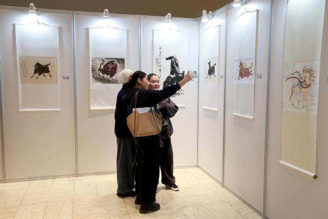 (260311) -- BISHKEK, March 11, 2026 (Xinhua) -- Visitors view exhibits at a Chinese painting exhibition on the theme of "horse" in Bishkek, Kyrgyzstan, on March 10, 2026. The exhibition opened here on Tuesday, showcasing about 50 works on horses in different styles by renowned Chinese painters. (Photo by Roman/Xinhua)