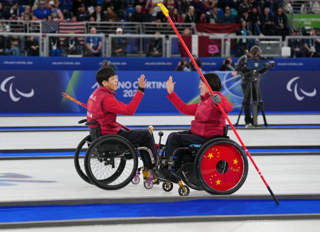 (260312) -- CORTINA D'AMPEZZO, March 12, 2026 (Xinhua) -- Wang Meng (R)/Yang Jinqiao of China celebrate during the wheelchair curling mixed doubles gold medal game between China and South Korea at the Milan-Cortina 2026 Paralympic Winter Games in Cortina D'ampezzo, Italy, March 11, 2026. (Xinhua/Mu Yu)