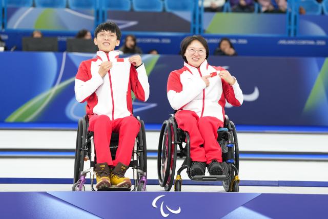 (260312) -- CORTINA D'AMPEZZO, March 12, 2026 (Xinhua) -- Gold medalists Yang Jinqiao (L)/Wang Meng of China pose during the awarding ceremony for the wheelchair curling mixed doubles event at the Milan-Cortina 2026 Paralympic Winter Games in Cortina D'ampezzo, Italy, March 11, 2026. (Xinhua/Lian Yi)