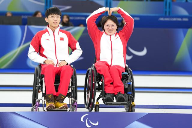 (260312) -- CORTINA D'AMPEZZO, March 12, 2026 (Xinhua) -- Gold medalists Yang Jinqiao (L)/Wang Meng of China pose during the awarding ceremony for the wheelchair curling mixed doubles event at the Milan-Cortina 2026 Paralympic Winter Games in Cortina D'ampezzo, Italy, March 11, 2026. (Xinhua/Lian Yi)