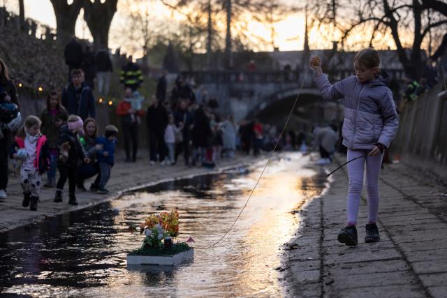 (260312) -- LJUBLJANA, March 12, 2026 (Xinhua) -- A girl walks alongside her float on a stream to celebrate the arrival of spring in Ljubljana, Slovenia, March 11, 2026. According to the Slovenian old calendar, March 12 marks the start of spring. It is a local tradition to send off floats downstream on March 11 to celebrate spring's arrival. (Photo by Zeljko Stevanic/Xinhua)