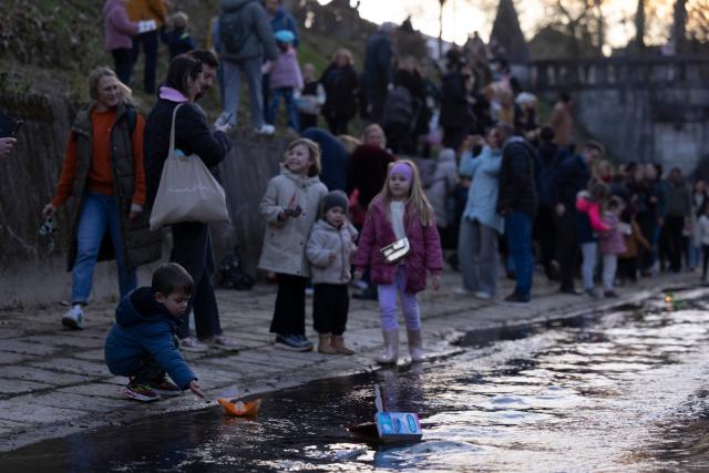 (260312) -- LJUBLJANA, March 12, 2026 (Xinhua) -- A boy releases a float on a stream to celebrate the arrival of spring in Ljubljana, Slovenia, March 11, 2026. According to the Slovenian old calendar, March 12 marks the start of spring. It is a local tradition to send off floats downstream on March 11 to celebrate spring's arrival. (Photo by Zeljko Stevanic/Xinhua)
