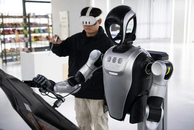 (260312) -- BEIJING, March 12, 2026 (Xinhua) -- A technician teaches a humanoid robot to use a wrench to tighten a screw at a data collection pre-training center for humanoid robots in Hefei, east China's Anhui Province, Dec. 4, 2025. (Xinhua/Zhang Duan)