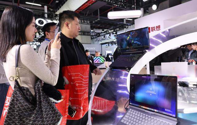 (260312) -- SHANGHAI, March 12, 2026 (Xinhua) -- Visitors view a laptop with an expandable screen during the 2026 Appliance & Electronics World Expo (AWE2026) in east China's Shanghai, March 12, 2026. The AWE2026 kicked off in Shanghai on Thursday. More than 1,200 enterprises from all over the world gathered at the expo to showcase their latest innovations. (Xinhua/Fang Zhe)