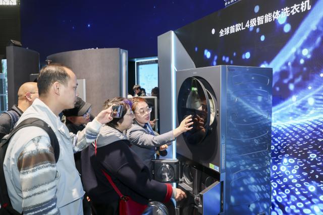 (260312) -- SHANGHAI, March 12, 2026 (Xinhua) -- Visitors learn about a smart washing machine during the 2026 Appliance & Electronics World Expo (AWE2026) in east China's Shanghai, March 12, 2026. The AWE2026 kicked off in Shanghai on Thursday. More than 1,200 enterprises from all over the world gathered at the expo to showcase their latest innovations. (Xinhua/Wang Xiang)