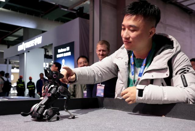 (260312) -- SHANGHAI, March 12, 2026 (Xinhua) -- A visitor interacts with a robotic dog during the 2026 Appliance & Electronics World Expo (AWE2026) in east China's Shanghai, March 12, 2026. The AWE2026 kicked off in Shanghai on Thursday. More than 1,200 enterprises from all over the world gathered at the expo to showcase their latest innovations. (Xinhua/Fang Zhe)