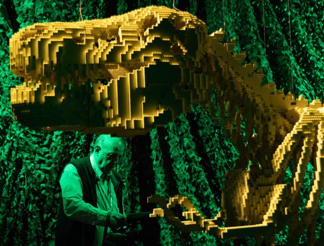 (260313) -- TORONTO, March 13, 2026 (Xinhua) -- A media member films the artwork "DINOSAUR SKELETON" on display during the exhibition Art of the Brick in Toronto, Canada, on March 12, 2026. Showcasing over 130 artworks and constructions made out of more than one million LEGO bricks, this art exhibition is held here from March 5 to May 31. (Photo by Zou Zheng/Xinhua)