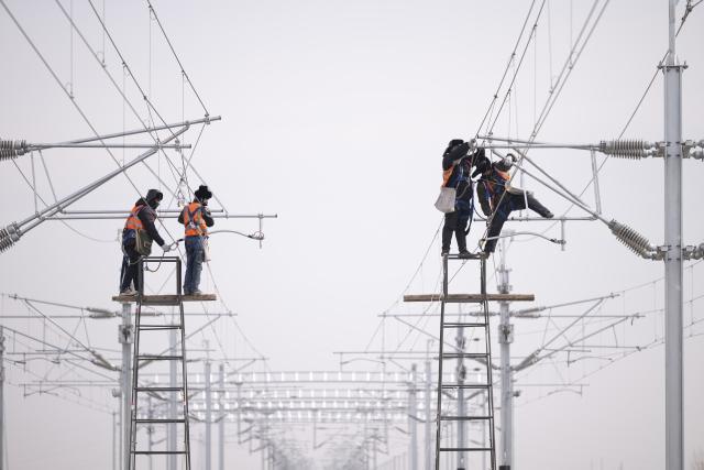 (260313) -- HARBIN, March 13, 2026 (Xinhua) -- Workers install catenary systems at the construction site of Suihua South Station of the Harbin-Yichun high-speed railway in Suihua, northeast China's Heilongjiang Province, March 13, 2026. Workers from China Railway Wuhan Electrification Bureau Group are pressing ahead with the construction of the communication, signaling and power supply systems for the 318-kilometer Harbin-Yichun high-speed railway. At present, 90% of the project has been completed. (Xinhua/Zhang Tao)