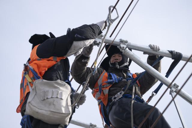 (260313) -- HARBIN, March 13, 2026 (Xinhua) -- Workers install catenary systems at the construction site of Suihua South Station of the Harbin-Yichun high-speed railway in Suihua, northeast China's Heilongjiang Province, March 13, 2026. Workers from China Railway Wuhan Electrification Bureau Group are pressing ahead with the construction of the communication, signaling and power supply systems for the 318-kilometer Harbin-Yichun high-speed railway. At present, 90% of the project has been completed. (Xinhua/Zhang Tao)