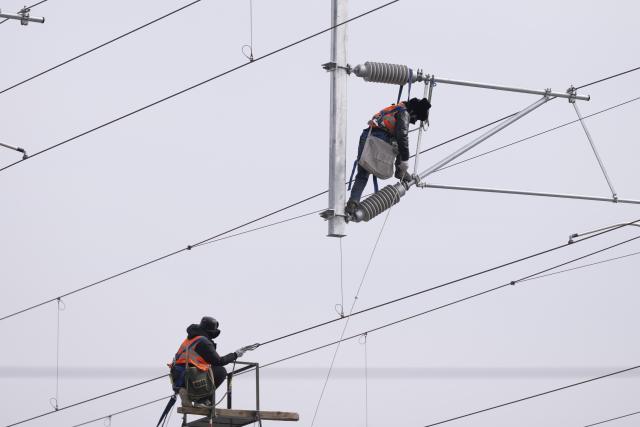 (260313) -- HARBIN, March 13, 2026 (Xinhua) -- Workers install catenary systems at the construction site of Suihua South Station of the Harbin-Yichun high-speed railway in Suihua, northeast China's Heilongjiang Province, March 13, 2026. Workers from China Railway Wuhan Electrification Bureau Group are pressing ahead with the construction of the communication, signaling and power supply systems for the 318-kilometer Harbin-Yichun high-speed railway. At present, 90% of the project has been completed. (Xinhua/Zhang Tao)