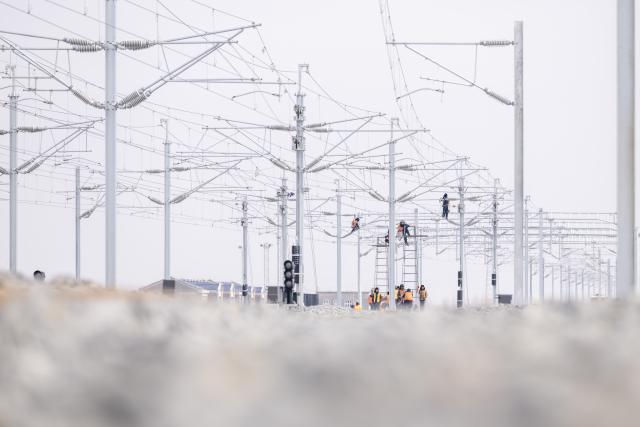 (260313) -- HARBIN, March 13, 2026 (Xinhua) -- Workers install catenary systems at the construction site of Suihua South Station of the Harbin-Yichun high-speed railway in Suihua, northeast China's Heilongjiang Province, March 13, 2026. Workers from China Railway Wuhan Electrification Bureau Group are pressing ahead with the construction of the communication, signaling and power supply systems for the 318-kilometer Harbin-Yichun high-speed railway. At present, 90% of the project has been completed. (Xinhua/Zhang Tao)