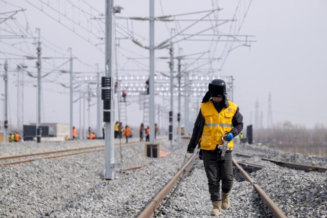 (260313) -- HARBIN, March 13, 2026 (Xinhua) -- A worker carries out surveying work at the construction site of Suihua South Station of the Harbin-Yichun high-speed railway in Suihua, northeast China's Heilongjiang Province, March 13, 2026. Workers from China Railway Wuhan Electrification Bureau Group are pressing ahead with the construction of the communication, signaling and power supply systems for the 318-kilometer Harbin-Yichun high-speed railway. At present, 90% of the project has been completed. (Xinhua/Zhang Tao)