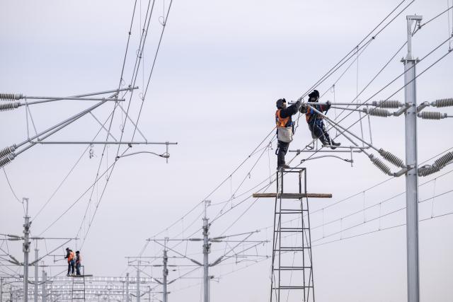 (260313) -- HARBIN, March 13, 2026 (Xinhua) -- A worker installs catenary systems at the construction site of Suihua South Station of the Harbin-Yichun high-speed railway in Suihua, northeast China's Heilongjiang Province, March 13, 2026. Workers from China Railway Wuhan Electrification Bureau Group are pressing ahead with the construction of the communication, signaling and power supply systems for the 318-kilometer Harbin-Yichun high-speed railway. At present, 90% of the project has been completed. (Xinhua/Zhang Tao)
