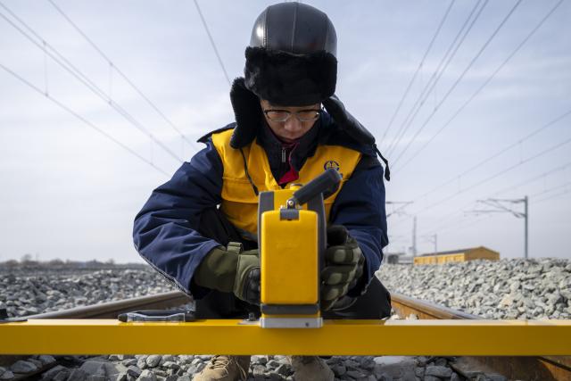 (260313) -- HARBIN, March 13, 2026 (Xinhua) -- A worker carries out surveying work at the construction site of Suihua South Station of the Harbin-Yichun high-speed railway in Suihua, northeast China's Heilongjiang Province, March 13, 2026. Workers from China Railway Wuhan Electrification Bureau Group are pressing ahead with the construction of the communication, signaling and power supply systems for the 318-kilometer Harbin-Yichun high-speed railway. At present, 90% of the project has been completed. (Xinhua/Zhang Tao)