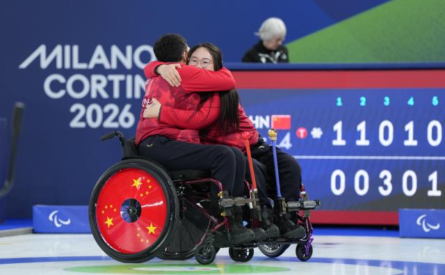 (260313) -- CORTINA D'AMPEZZO, March 13, 2026 (Xinhua) -- Li Nana (R) of China celebrates with teammate Chen Jianxin after the wheelchair curling mixed team semifinal match between China and Sweden at the Milan-Cortina 2026 Paralympic Winter Games in Cortina D'ampezzo, Italy, March 13, 2026. (Xinhua/Wang Kaiyan)
