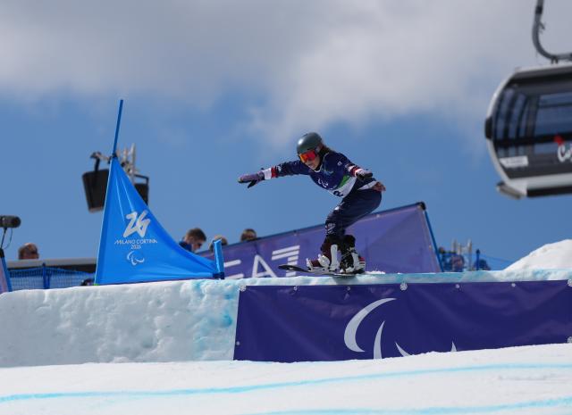 (260313) -- CORTINA D'AMPEZZO, March 13, 2026 (Xinhua) -- Kate Delson of the United States competes during the Para Snowboard Women's Banked Slalom SB-LL2 event at the Milan-Cortina 2026 Paralympic Winter Games in Cortina D'ampezzo, Italy, March 13, 2026. (Xinhua/Mu Yu)